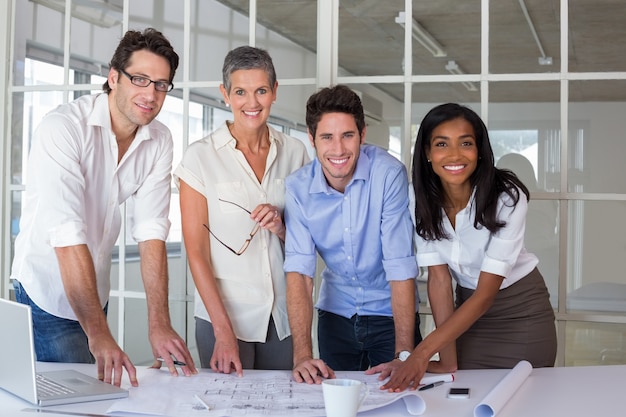 Une équipe d&#39;architectes examinant des plans en souriant à la caméra