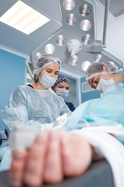 Une équipe chirurgicale concentrée opérant un patient dans une salle d'opération Un anesthésiste bien formé avec des années de formation avec des machines complexes suit le patient tout au long de la chirurgie