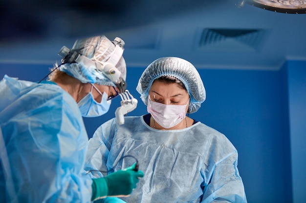 Une équipe de chirurgiens effectue une opération invasive. Portrait de close-up de chirurgiens. Travailler avec un instrument de coagulation, la coagulation vasculaire