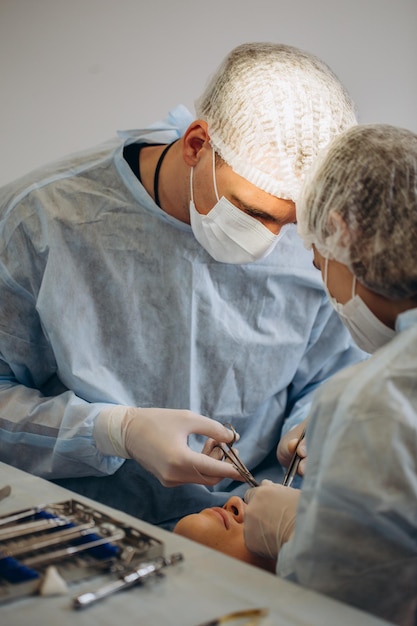 Une équipe de chirurgiens en uniforme effectue une opération sur un patient à la clinique de chirurgie plastique