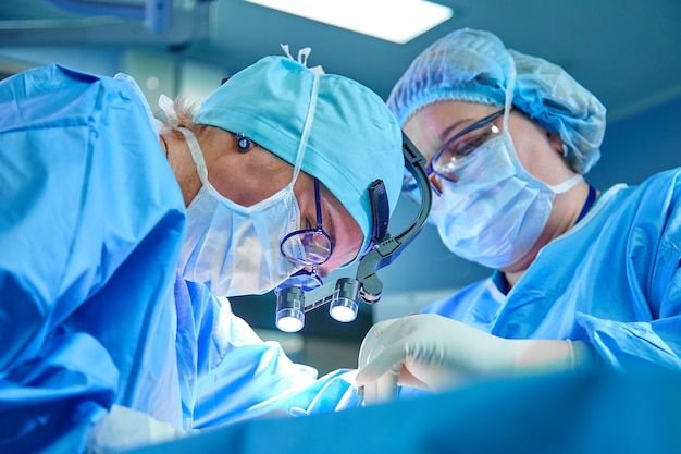 Une équipe de chirurgiens en uniforme effectue une opération sur un patient dans une clinique de chirurgie cardiaque. Médecine moderne, une équipe professionnelle de chirurgiens, santé.