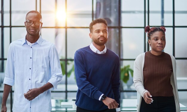 Photo Équipe commerciale afro-américaine réussie debout avec les bras croisés au bureau