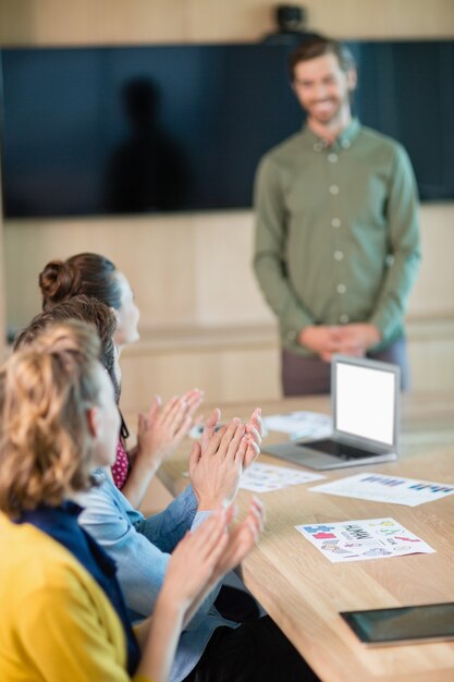 L'équipe Commerciale Applaudissant Leur Collègue Dans La Salle De Conférence