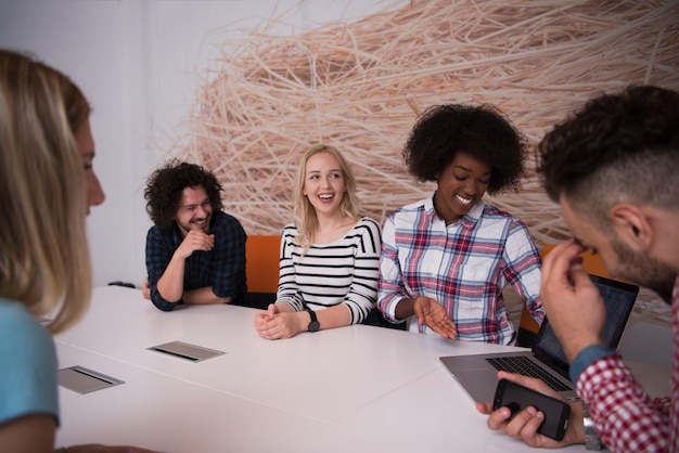 Photo Équipe commerciale de démarrage multiethnique lors d'une réunion dans un brainstorming intérieur de bureau moderne et lumineux, travaillant sur un ordinateur portable et une tablette