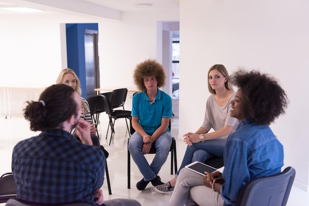 Photo Équipe commerciale de démarrage multiethnique lors d'une réunion dans un brainstorming intérieur de bureau moderne et lumineux, travaillant sur un ordinateur portable et une tablette