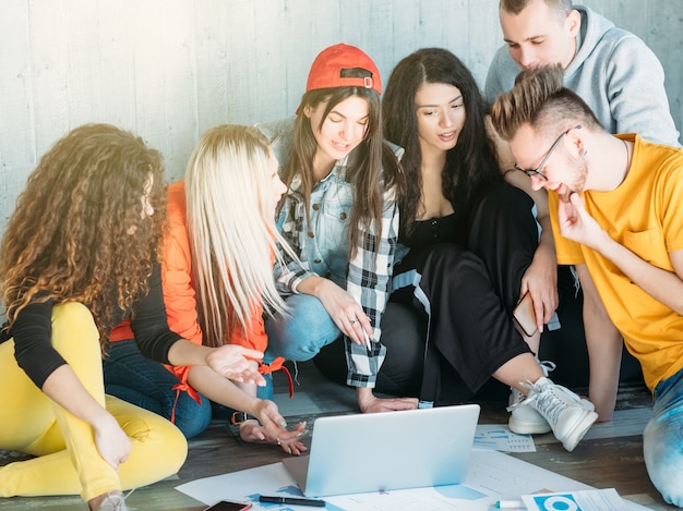 équipe commerciale millénaire travaillant ensemble. groupe de jeunes diversifié assis sur le sol.