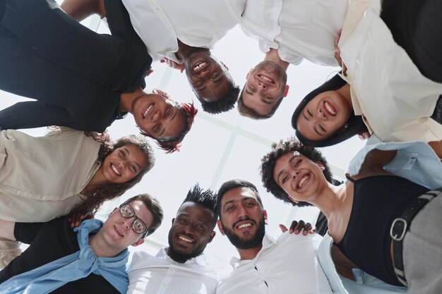 Une équipe commerciale professionnelle diversifiée et heureuse se tient au bureau en regardant la caméra