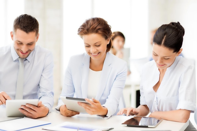 équipe commerciale souriante travaillant avec des tablettes au bureau