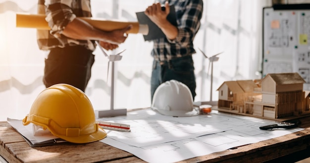 L'équipe de construction se serre la main pour saluer le lancement d'un nouveau plan de projet derrière un casque jaune sur le bureau du bureau pour consulter son projet de constructionxA