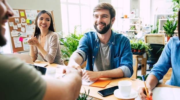 Une équipe de démarrage moderne et heureuse en vêtements décontractés au bureau ou dans un espace de travail collaboratif travaille et discute des plans et des idées