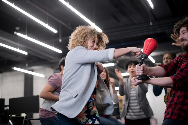 une équipe de démarrage multiethnique de développeurs de logiciels s'amusant en boxant au bureau, des employés divers excités riant en profitant d'une activité amusante pendant la pause de travail, des travailleurs créatifs et sympathiques jouant