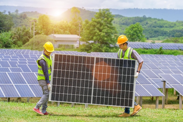 Une équipe de deux hommes asiatiques installe des panneaux solaires Travaille sur l'installation de panneaux solaires dans une centrale solaire