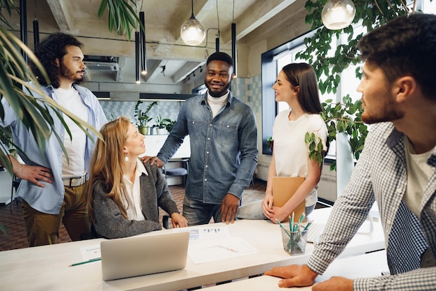 Une équipe de divers collègues dans un bureau moderne discute ensemble de leur projet