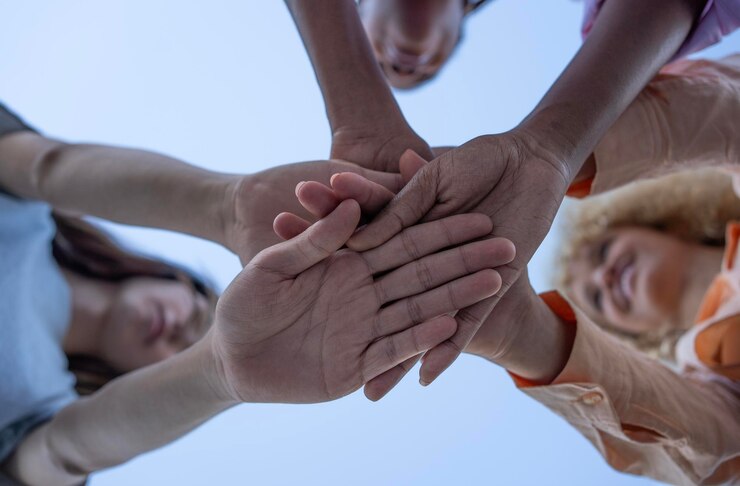 Photo équipe diversifiée joignant les mains d'un groupe métis de jeunes en cercle et joignant les mains