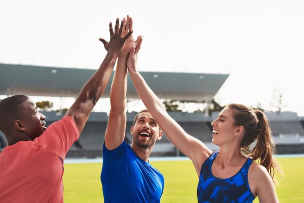 Photo Équipe de diversité et high five sur la piste du stade pour faire de l'exercice ou s'entraîner ensemble en athlétisme groupe touchant les mains en signe de célébration ou de solidarité pour faire de l'exercice ou gagner en fitness