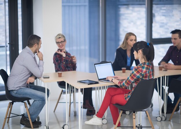 Équipe d'entreprise de démarrage lors d'une réunion dans un brainstorming intérieur de bureau moderne et lumineux, travaillant sur un ordinateur portable et une tablette