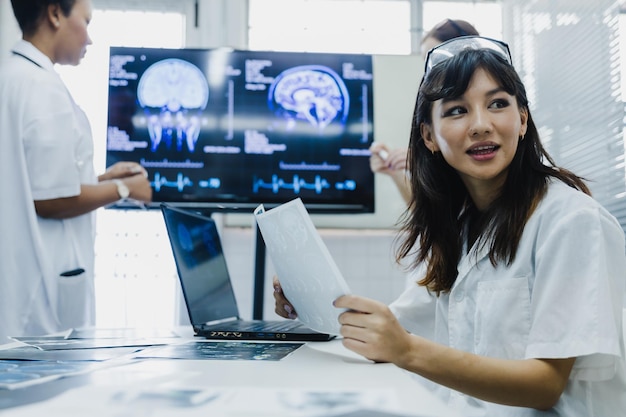 Une équipe de femmes médecins vérifie les résultats des scans sur papier et regarde les moniteurs en laboratoire, partage des connaissances et de l'expérience médicales et bénéficie de ses collègues et des patients avant la chirurgie et le traitement.