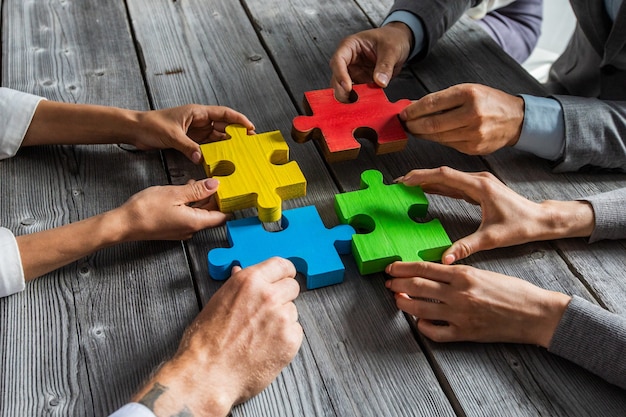 L'équipe de gens d'affaires assis autour d'une table de réunion et l'assemblage de pièces de puzzle couleur concept d'idées de coopération de l'unité