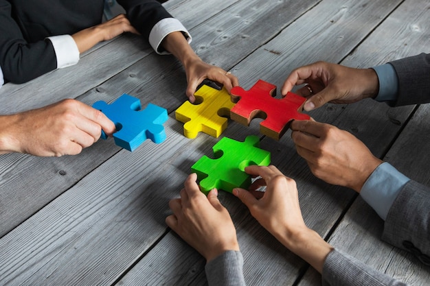 Photo Équipe de gens d'affaires assis autour d'une table de réunion et assemblant des pièces de puzzle de couleur concept d'idées de coopération d'unité