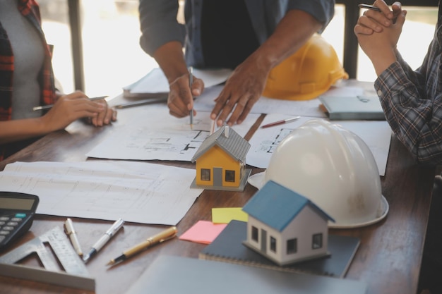 Une équipe d'ingénieurs de la construction s'entretient avec les gestionnaires et les ouvriers de la construction sur le chantier de construction Plan de travail d'inspection de la qualité Projet de conception de bâtiments domestiques et industriels