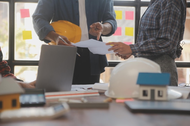 Une équipe d'ingénieurs de la construction s'entretient avec les gestionnaires et les ouvriers de la construction sur le chantier de construction Plan de travail d'inspection de la qualité Projet de conception de bâtiments domestiques et industriels