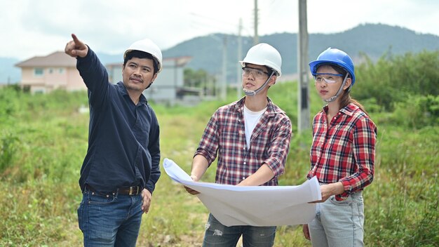 L'équipe d'ingénieurs discute et travaille sur le chantier de construction. Inspection par le propriétaire du projet de village et de la construction immobilière.