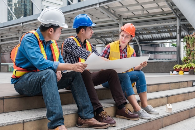 Équipe D'ingénieurs Multiethniques Se Réunissant Et Discutant Avec Un Plan Pour Un Nouveau Projet De Chantier De Construction En Milieu Urbain