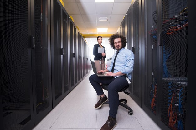 Photo une équipe de jeunes techniciens travaillant ensemble sur des serveurs au centre de données à l'aide d'ordinateurs portables et de tablettes