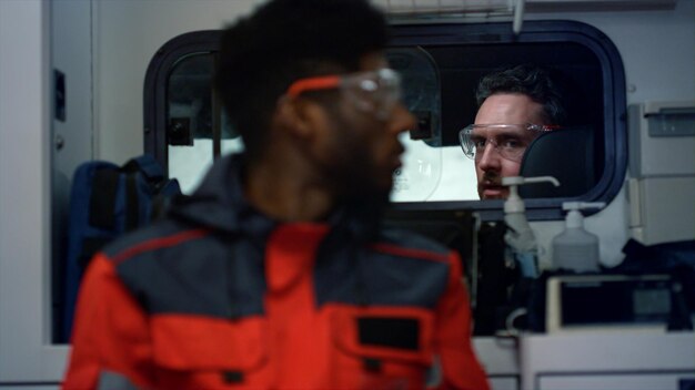 Photo une équipe médicale multiethnique effectuant un appel d'urgence dans une ambulance. un ambulancier afro-américain assis dans un véhicule d'urgence. un chauffeur d'ambulance et un médecin parlent au travail.