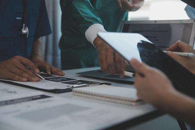 Photo Équipe médicale multiraciale ayant une réunion avec des médecins en blouse blanche et en blouse chirurgicale assis à une table discutant des dossiers d'un patient