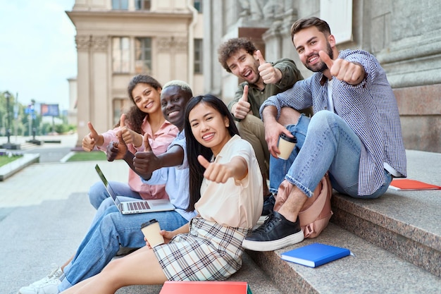 Équipe multiculturelle d'étudiants montrant les pouces vers le haut