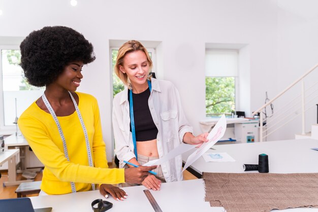 Photo Équipe multiethnique de créateurs de mode travaillant dans un atelier de création de vêtements - groupe multiracial de stylistes, de couturiers et de couturiers travaillant sur une nouvelle collection