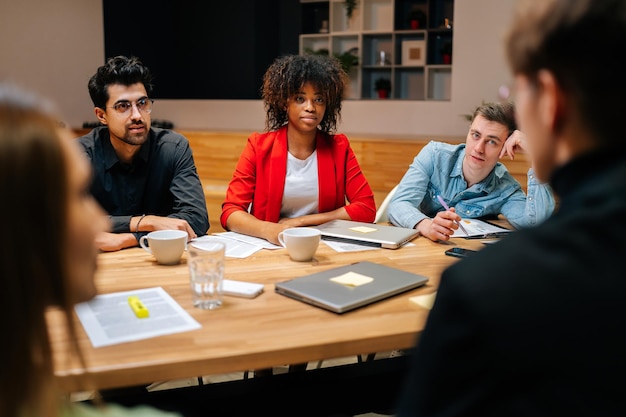 Équipe multiraciale négociant un projet développant une stratégie commerciale faisant une analyse de la paperasserie au bureau Partenaires commerciaux internationaux multiethniques discutant