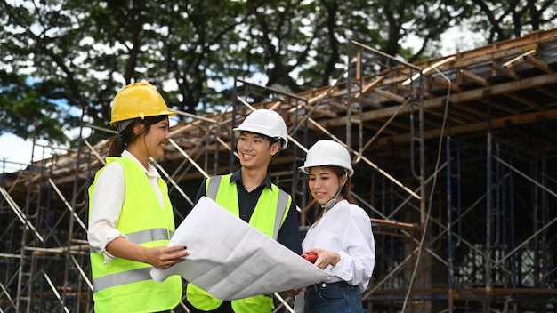 Équipe de spécialistes et ingénieur civil inspectant le chantier de construction de bâtiments industriels