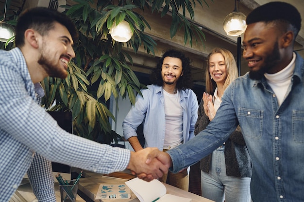 Équipe de travail de bureau saluant leur nouvel employé masculin afro-américain
