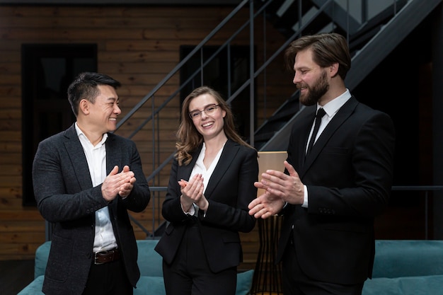 Photo une équipe de trois employés s'applaudit debout