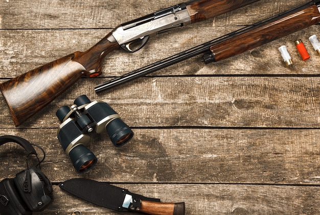 Photo Équipement de chasse sur le vieux fond en bois comprenant des jumelles et des cartouches de couteau de fusil