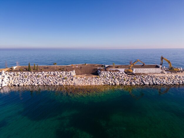 L'équipement de construction lourd construit un brise-lames brise-lames en construction dans la mer Vue aérienne