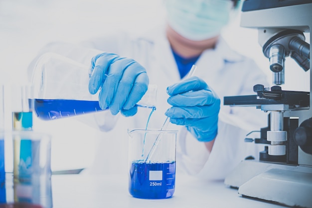Équipement et expériences scientifiques scientifique verseur d'huile avec tube à essai bleu faisant des recherches en laboratoire.