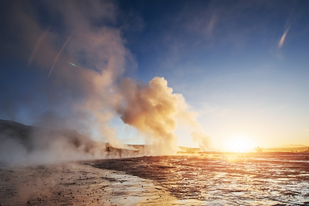 Eruption du geyser de Strokkur en Islande. Des couleurs fantastiques brillent à travers la vapeur. Beaux nuages roses dans un ciel bleu