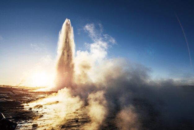 Éruption du geyser Strokkur en Islande Les couleurs froides de l'hiver L'éclairage du soleil à travers la vapeur