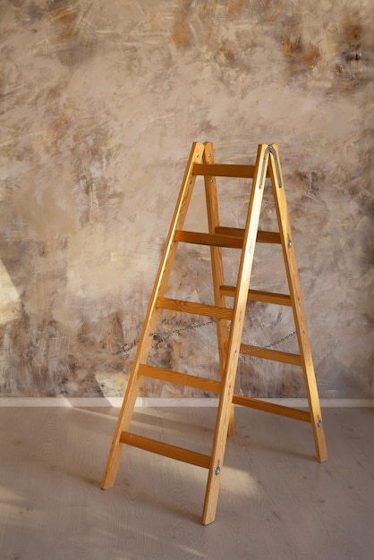 Escabeau en bois dans le contexte d'un mur de béton texturé sur une journée ensoleillée