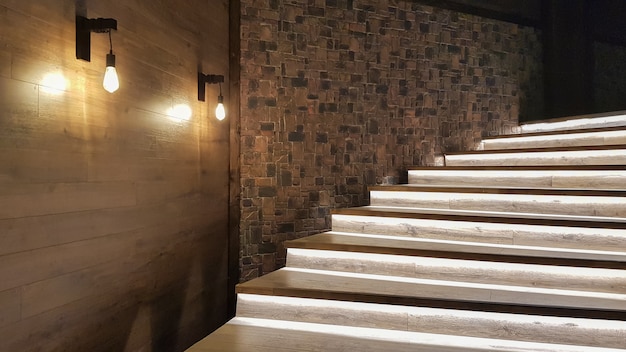 Escalier lumineux avec marches en bois et illuminé la nuit à l'intérieur d'une grande maison