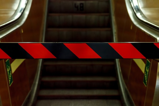 Escalier mécanique fermé dans le métro. Vue de dessous. Réparation d'escalators, pas d'entrée, passage fermé. Bandes rouges et noires sur la barrière interdisant. L'escalator s'est arrêté. Espace pour votre étiquette et publicité