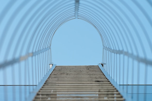 Escalier de secours. Long escalier en métal sur la façade en verre bleu du bureau, du bâtiment industriel ou du centre commercial. Sortie de secours, vue de dessous. Concept d'escalier vers le ciel. Mise au point sélective.