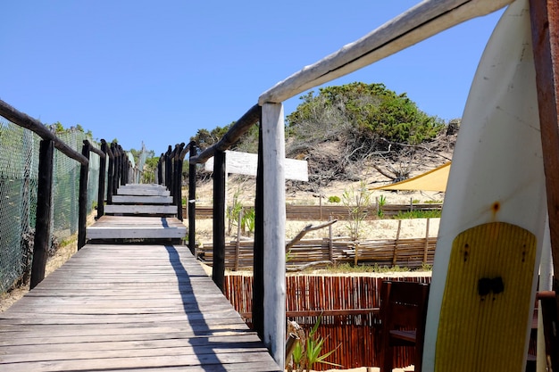 Escaliers en bois menant à la dune de sable Il y a une planche de surf à proximité