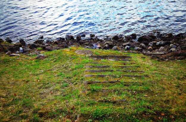 Photo des escaliers couverts d'herbe vers le paysage rocheux de la rive de la rivière