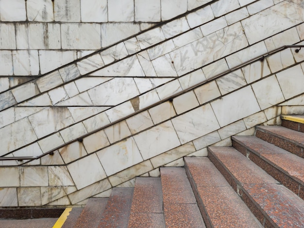 Escaliers menant au passage souterrain ou à la station de métro Vue latérale d'un escalier vide avec un mur bordé d'escaliers en marbre et en granit rouge