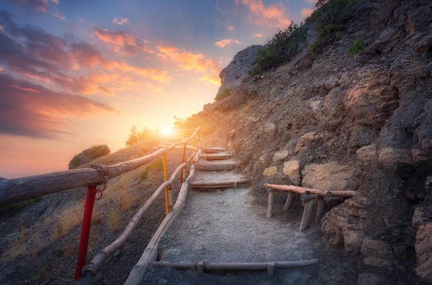 Escaliers en pierre avec garde-corps en bois dans les montagnes au coucher du soleil