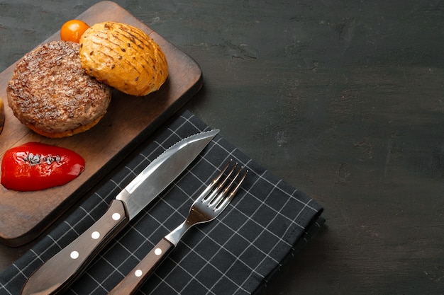 Escalope de burger grillé avec un petit pain sur planche de bois, vue de dessus